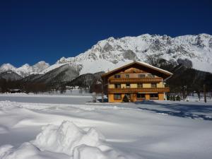 a log cabin in the snow with a mountain at Ferienwohnung Alpenecho in Ramsau am Dachstein