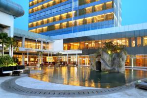 a building with a fountain in front of a building at Resinda Hotel Karawang in Karawang