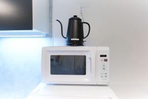 eine Kaffeekanne auf einer Mikrowelle in der Unterkunft Bellie Sangenjaya by Tranova in Tokio