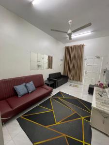een woonkamer met een rode bank en een zwart-geel vloerkleed bij Aufa Homestay 3 Bilik Aircond in Gua Sai