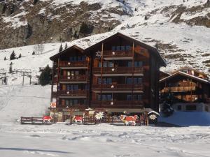 ein großes Blockhaus im Schnee mit Kühen davor in der Unterkunft Apartment Edelweiss in Riederalp