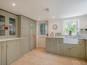 una cucina con armadi bianchi e un orologio sul muro di Hope Cottage a Ilketshall Saint Andrew