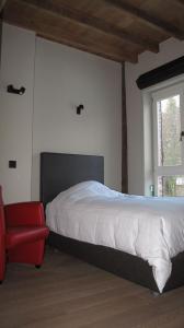 a bedroom with a bed and a red chair at Hotel Guesthouse Begijnhof in Leuven