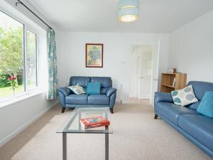 a living room with two blue couches and a table at Little Orchard in Farmborough
