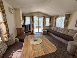 a living room with a couch and a table at Gorgeous 6 Berth Caravan With Decking Area, Dovercourt Holiday Park Ref 44510A in Great Oakley