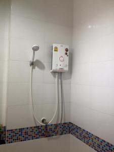 a shower in a bathroom with ailed wall at Hobby Hotel in Uttaradit