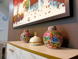 three vases sitting on a counter under a painting at Sarrah Homestay At Kasa Height Residence in Kampong Alor Gajah