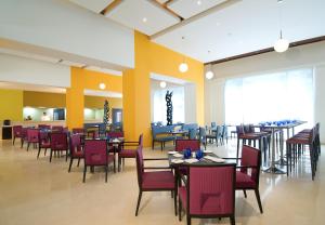 a dining room with tables and chairs and yellow walls at ibis Pune Viman Nagar - An Accor Brand in Pune