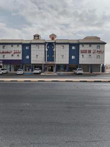 un edificio azul y blanco con coches estacionados frente a él en رؤوم إن للشقق المخدومة - Raoum Inn Serviced Apartments-Hotah, en Hotat bani tamim