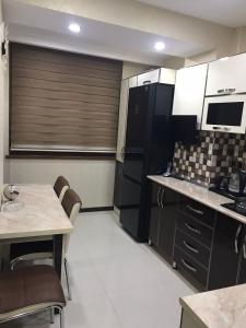 a kitchen with black and white cabinets and a table at Хорошем месте находится, улица Иззет Небиев 6-22 in Baku