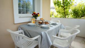 una mesa con cuatro sillas blancas y una mesa con comida. en Apartments Red Rose, en Nin