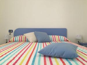 a bed with colorful sheets and pillows on it at Casa Rok in Donnalucata