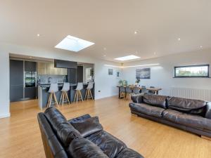 a living room with leather couches and a kitchen at Tregarden in Poundstock