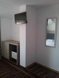 um quarto com uma televisão e um espelho na parede em Hotel La John em Vama Veche
