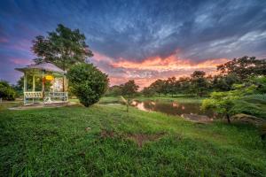 - un kiosque au bord d'une rivière avec un coucher de soleil dans l'établissement U Resort Nakhon Ratchasima, à Nakhon Ratchasima