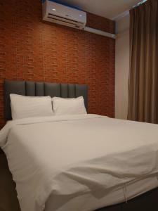 a bedroom with a white bed and a wall at Baan der Bruyn SHA in Jomtien Beach