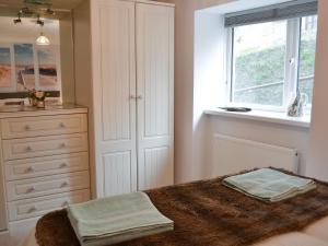 a bedroom with a bed with a dresser and a window at Roland Cottage in Falmouth