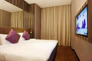 a hotel room with a bed and a flat screen tv at Aqueen Hotel Paya Lebar in Singapore