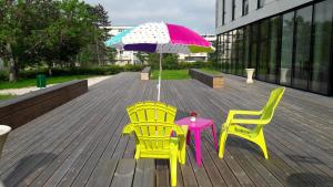 2 sillas y una mesa con sombrilla en la cubierta en Adonis Dijon Maison Internationale, en Dijon