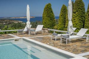 una piscina con 2 sillas y sombrillas en Villas Agia Irini Cove en Agia Irini Paros