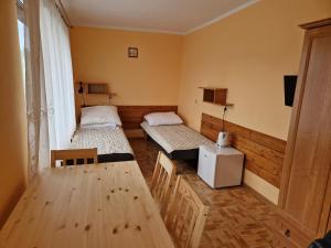 a small room with two beds and a table at Emides in Pobierowo