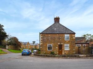 a brick house with a car parked in front of it at Tiddles Corner in Braunston +3 photos