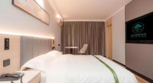 a bedroom with a white bed and a television at GreenTree Inn xinghua Middle Yingwu Road Express Hotel in Xinghua