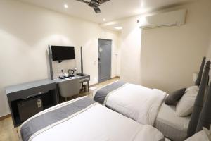 a hotel room with two beds and a television at Hotel Metro Prime in Kolkata
