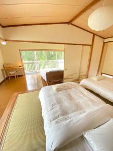 Un dormitorio con dos camas y una gran ventana. en COZY HOUSE Izukogen, en Ito