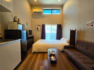 ein kleines Zimmer mit einem Bett und einer Couch in der Unterkunft Comfort CUBE PHOENIX Yakuin in Susakiuramachi