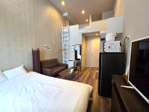 ein Schlafzimmer mit einem Bett, einem Fernseher und einem Stuhl in der Unterkunft Comfort CUBE PHOENIX Yakuin in Susakiuramachi