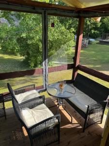 eine überdachte Veranda mit Tisch und Stühlen in der Unterkunft Forest Camping with grillhouse and dush in Lõupõllu