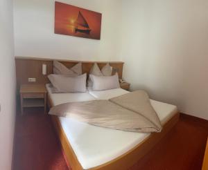 a small bedroom with a bed with white sheets at Strandhotel Faak in Faak am See +42 photos