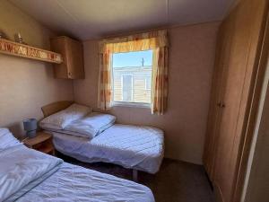 a small room with two beds and a window at Lovely 6 Berth Caravan At Naze Marine Holiday Park In Essex Ref 17003C in Walton-on-the-Naze