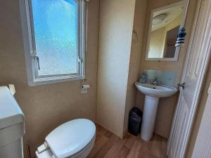 a bathroom with a toilet and a sink and a window at Lovely 6 Berth Caravan At Naze Marine Holiday Park In Essex Ref 17003C in Walton-on-the-Naze +16 photos