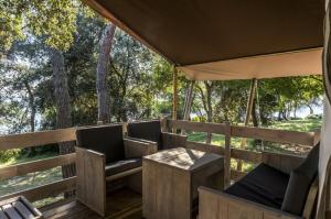 a porch with chairs and a table and trees at Easyatent FKK Safari tent Koversada Naturist - clothes free in Vrsar