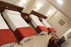 una camera d'albergo con tre letti con lenzuola rosse e bianche di Hotel Villa de Marin a Marín
