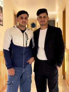 two men standing next to each other in a hallway at Rose Manor suites in Dehradun