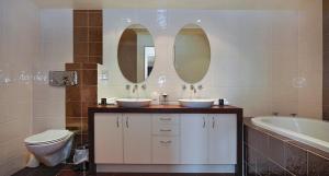 a bathroom with two sinks and a toilet and a tub at Pukaki Holiday Apartments in Rotorua
