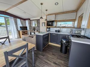 a kitchen and dining room with a table and a stove at Modern Caravan With Decking At Valley Farm, Essex Ref 46112V in Great Clacton