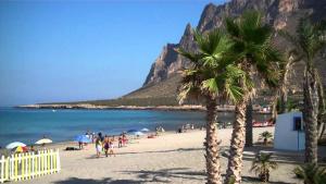 a group of people on a beach with palm trees at Appartamento Nonna Lina in Custonaci