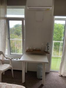 a white table in a room with two windows at Гостевой дом SUN TAG in Chornomors'ke