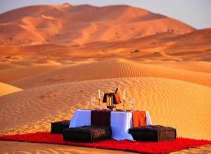 a table in the middle of a desert at Merzouga Luxury Camp in Merzouga