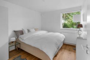 a white bedroom with a bed and a window at Villa Österlen på Viks fiskeläge in Simrishamn