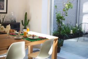 a dining room table with white chairs and a table with food on it at 4B B&B Brugge in Bruges