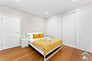a white bedroom with a bed with yellow pillows at Charming 3-Bedroom House in Beacon Hill in Oxford Falls