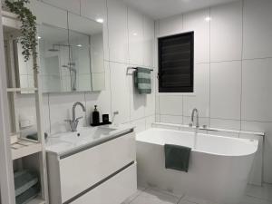 a white bathroom with a tub and a sink at SeaSide Serenity - beach 200m in Mudjimba +15 photos