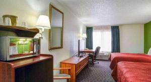 a hotel room with a television and a bed and a desk at Quality Inn & Suites Airport in Austin
