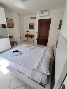 a bedroom with a bed with white sheets and a table at Alice e il mare in Alghero