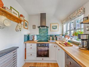 une cuisine avec des armoires blanches et un four à plaques de cuisson dans l'établissement Willow Tit Cottage, à Capel-Cynon